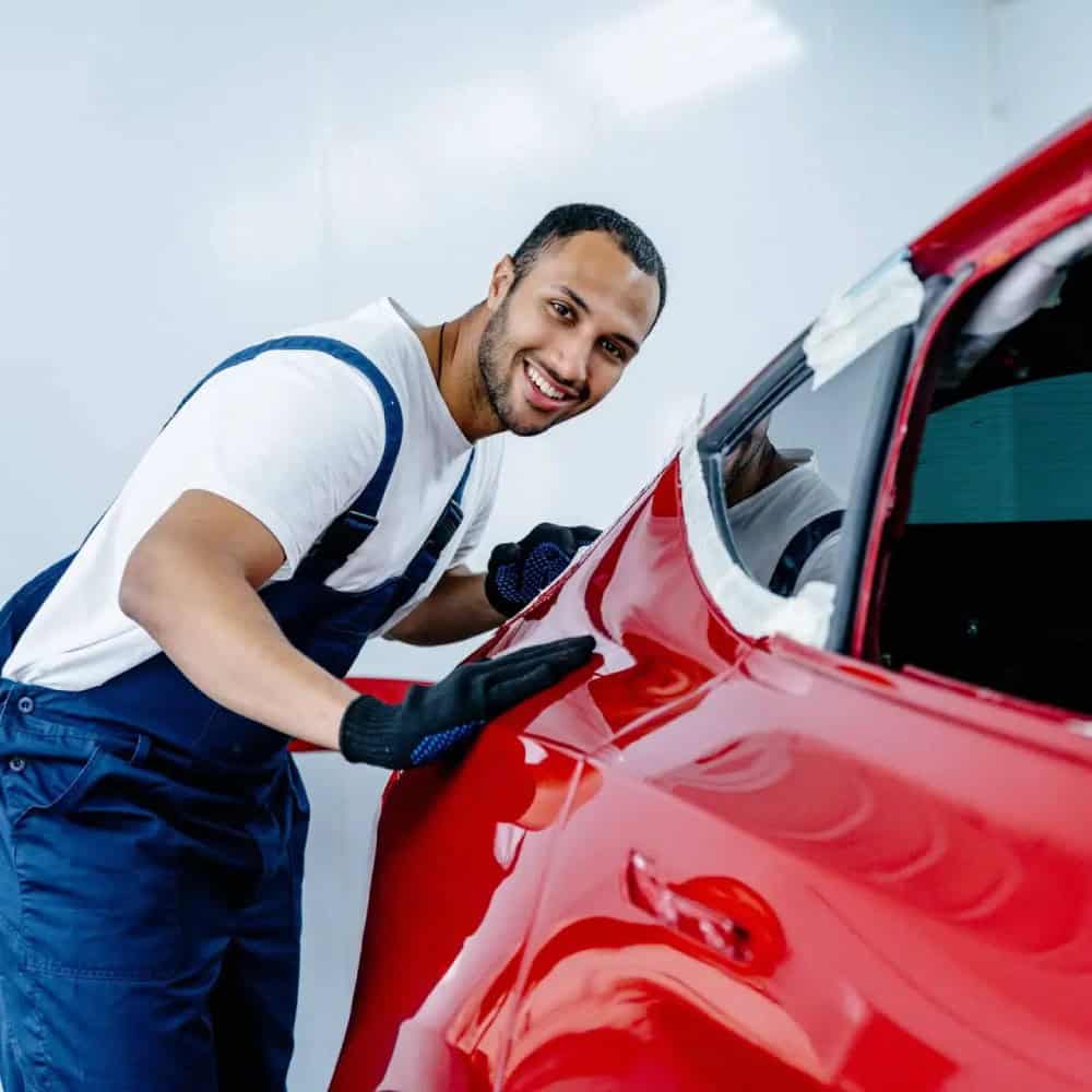 Car repair technician inspecting a red vehicle at Don Atwell and Associates, LLC. Auto repair technician working on a red car at Don Atwell and Associates, LLC.